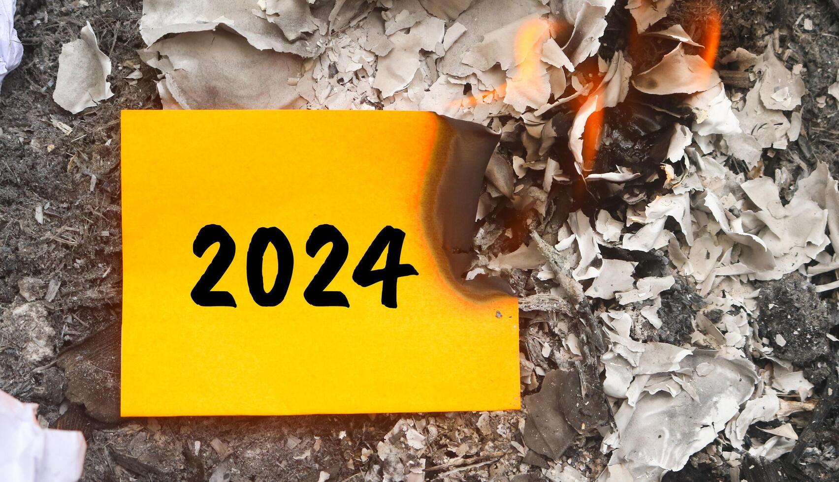 Paper burning on fire and pile of paper waste with 2024 written on it. new life and new year 2025 concept. 2024 paper is burning, say goodbye to 2024 photo