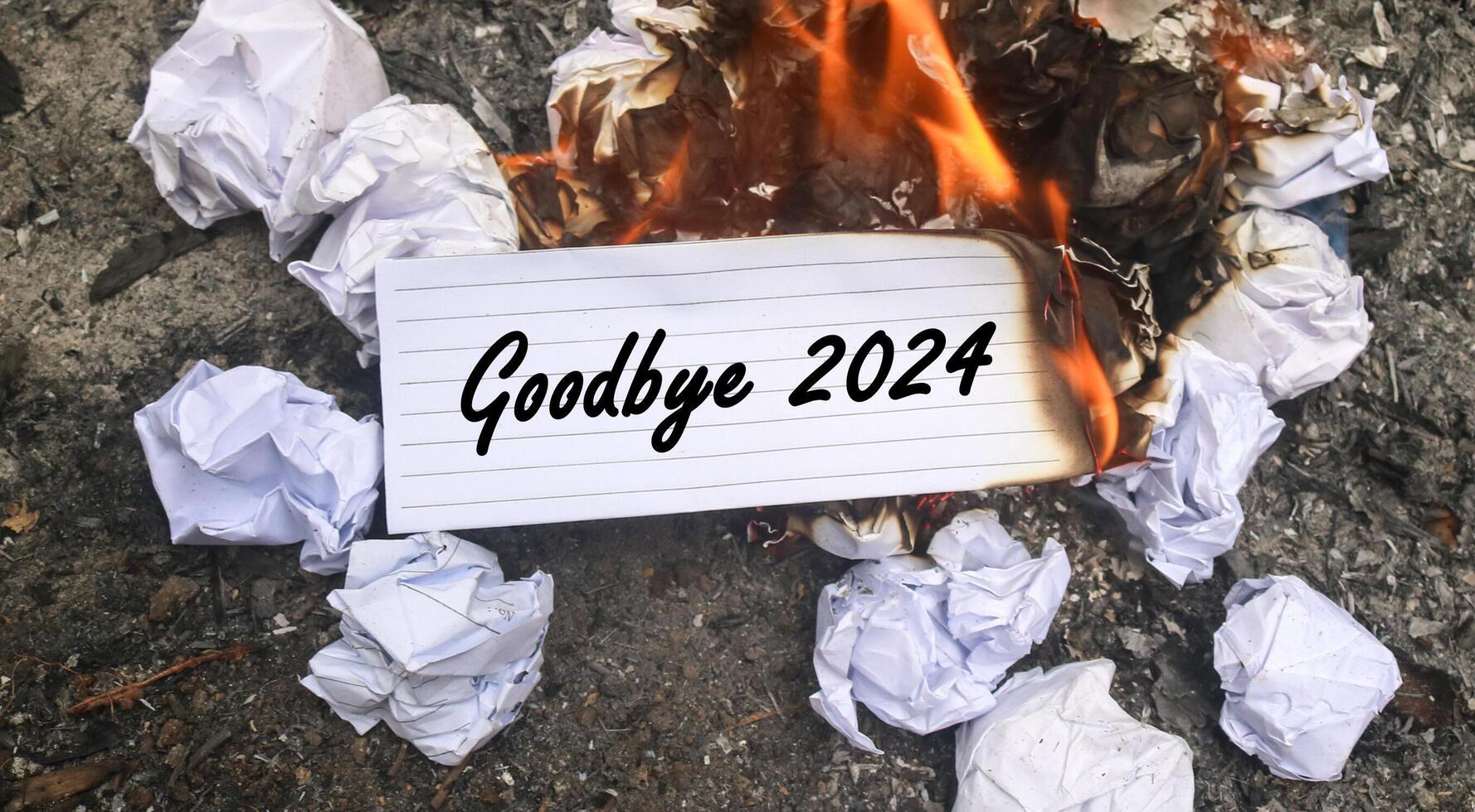 Paper is burning on fire and pile of paper waste with Goodbye 2024 written on it. new life and new year 2025 concept. 2024 paper is burning, say goodbye to 2024 photo