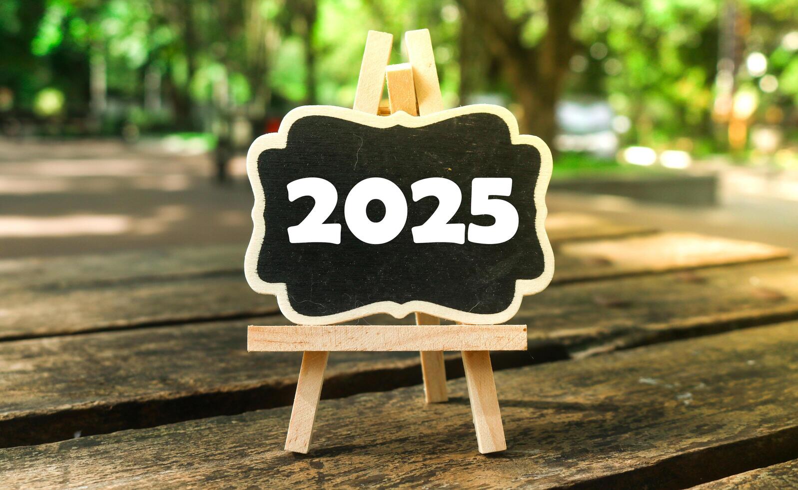 A small wooden-framed blackboard with 2025 written in white text on it. Hello new year 2025 photo