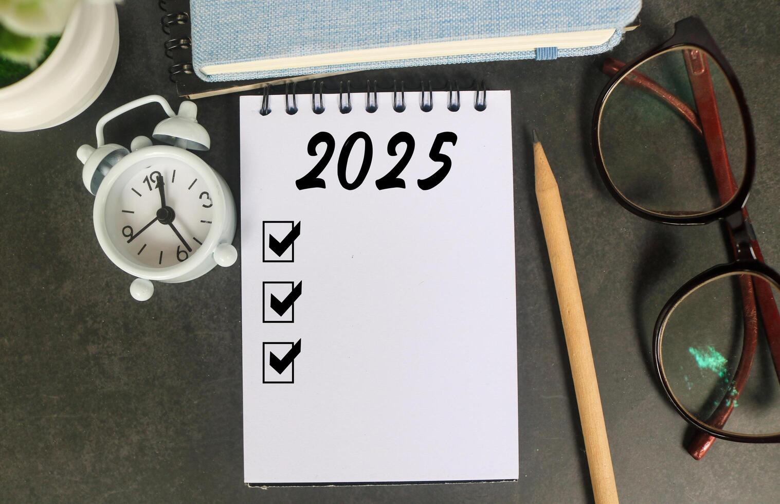 2025 New Year resolutions goals, plans, and resolutions concept. Planning checklist 2025 target on notebook with office desk background photo