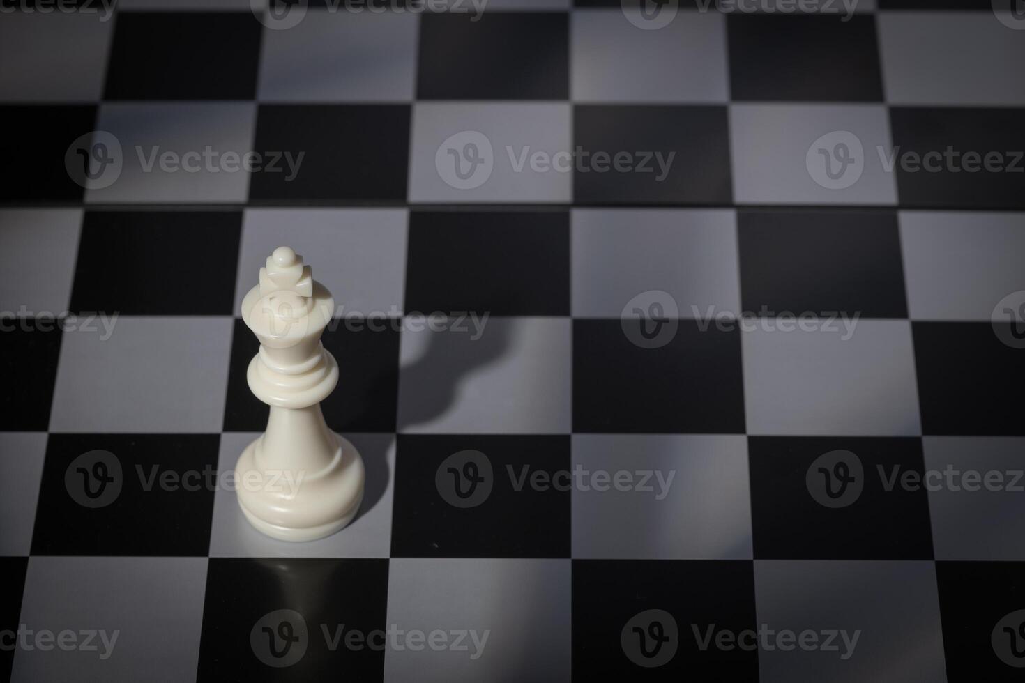 A close-up of a chessboard highlighting the white KING standing out among black pieces, symbolizing strategic thinking, leadership, and decisive planning in overcoming challenges and achieving goals. photo