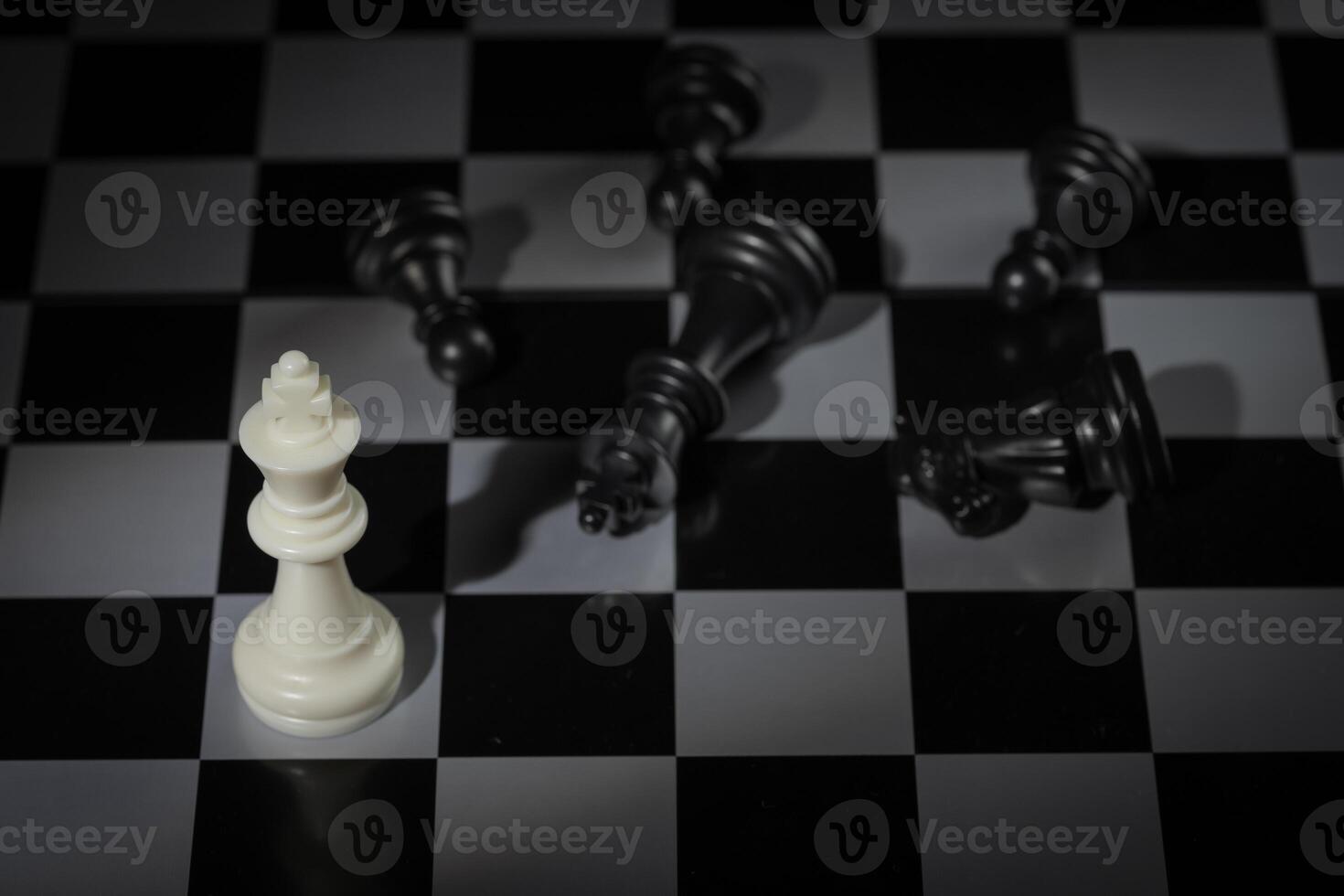 A close-up of a chessboard highlighting the white KING standing out among black pieces, symbolizing strategic thinking, leadership, and decisive planning in overcoming challenges and achieving goals. photo
