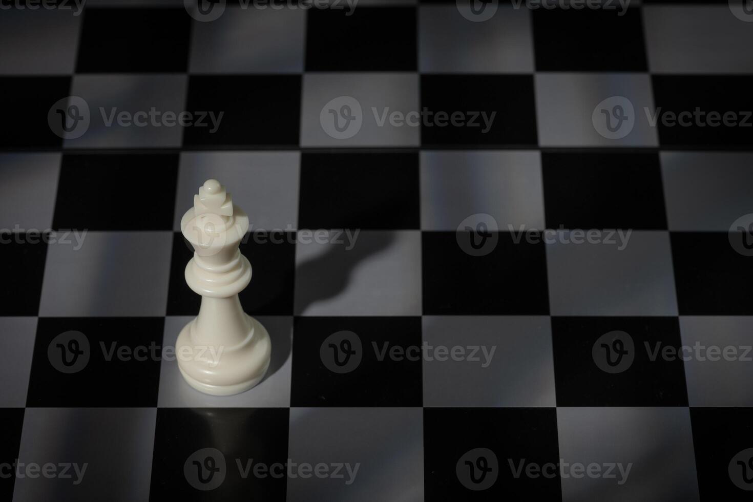 A close-up of a chessboard highlighting the white KING standing out among black pieces, symbolizing strategic thinking, leadership, and decisive planning in overcoming challenges and achieving goals. photo