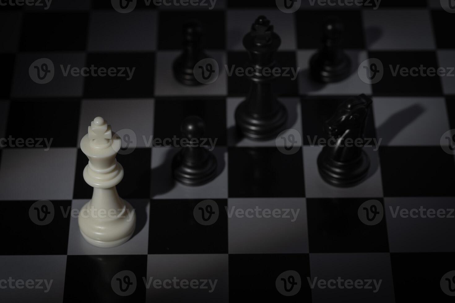 A close-up of a chessboard highlighting the white KING standing out among black pieces, symbolizing strategic thinking, leadership, and decisive planning in overcoming challenges and achieving goals. photo