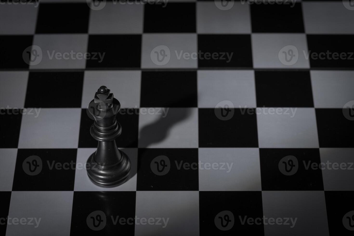 A close-up of a chessboard highlighting the white KING standing out among black pieces, symbolizing strategic thinking, leadership, and decisive planning in overcoming challenges and achieving goals. photo