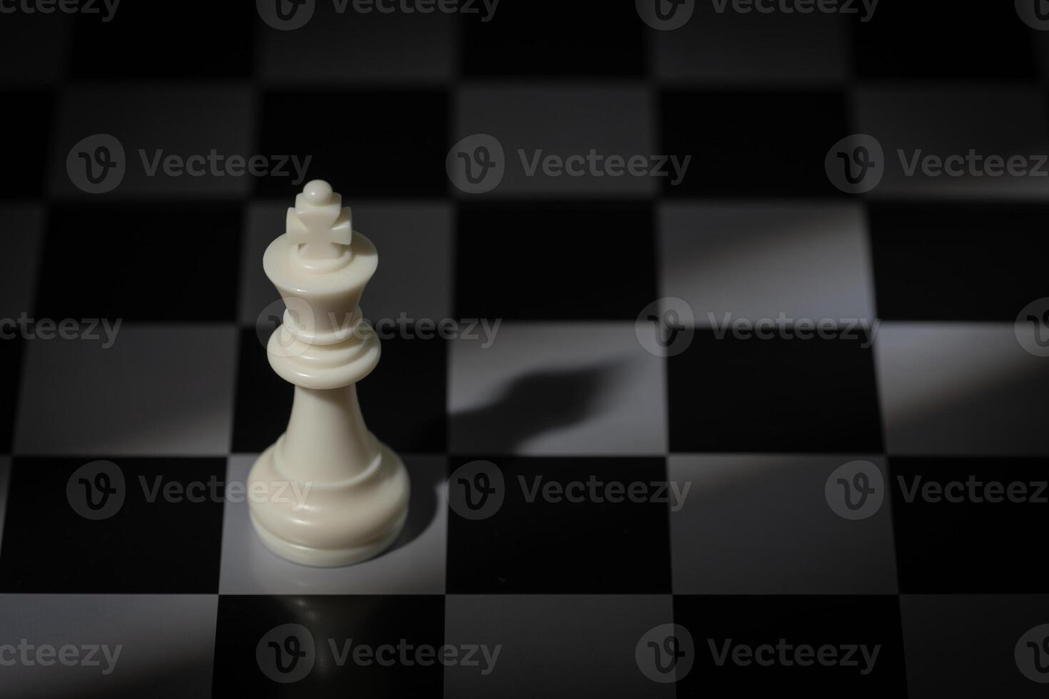 A close-up of a chessboard highlighting the white KING standing out among black pieces, symbolizing strategic thinking, leadership, and decisive planning in overcoming challenges and achieving goals. photo