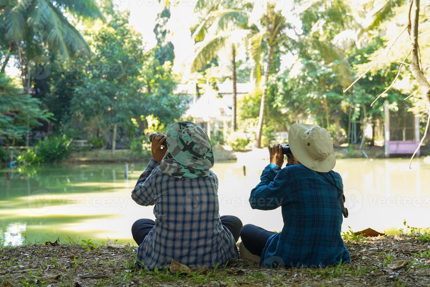 Two Asian boys use binoculars to study the local birds at school. Soft and selective focus. photo