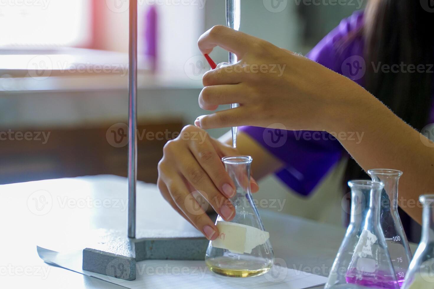 Close-up of a student performing an acid-base titration experiment. Concept of chemistry lab, science, experiment, skills, learning. photo