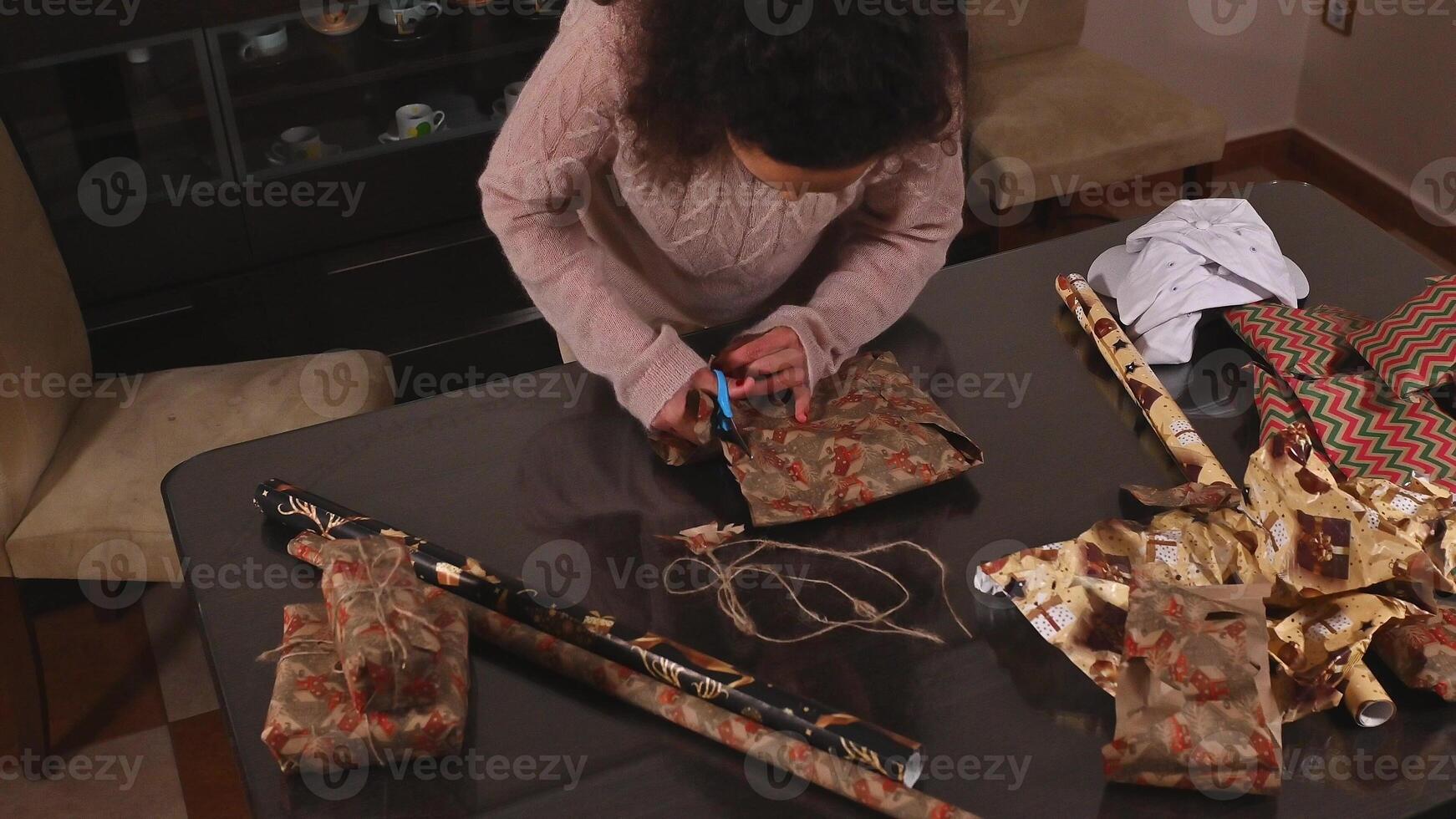 Woman Wrapping Christmas Gifts at Home with Brown Paper and Rustic String photo