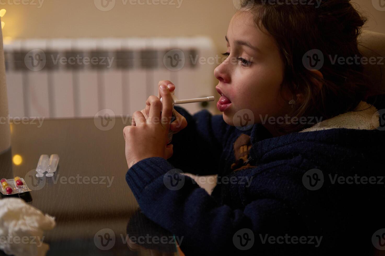 Child taking medication at home with a focused expression photo