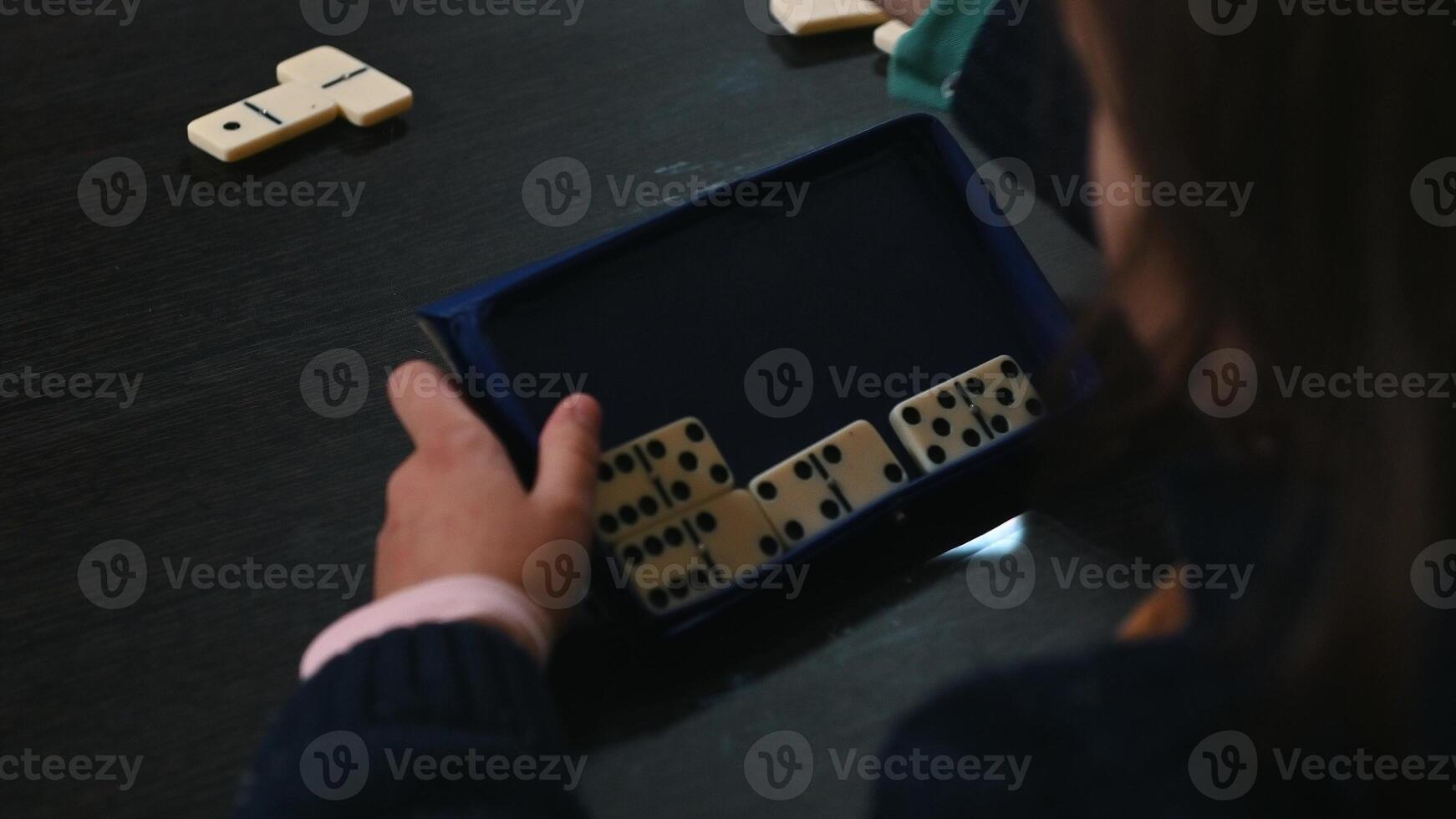 Child Engaged in Playing a Dominoes Tabletop Game on a Wooden Surface photo
