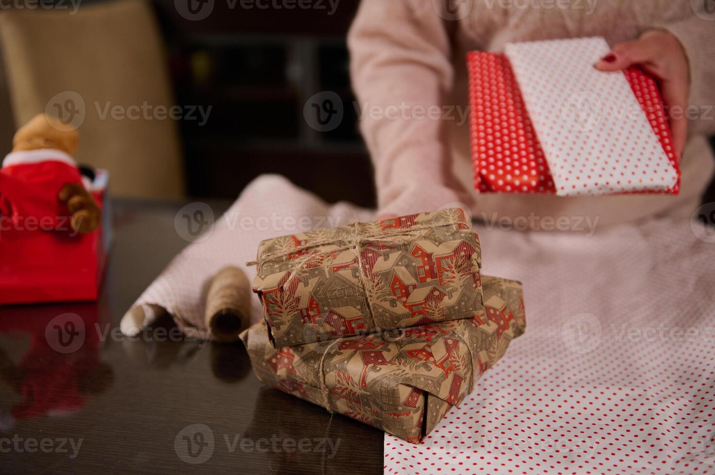 Woman wrapping gifts at a table with festive holiday wrapping paper photo