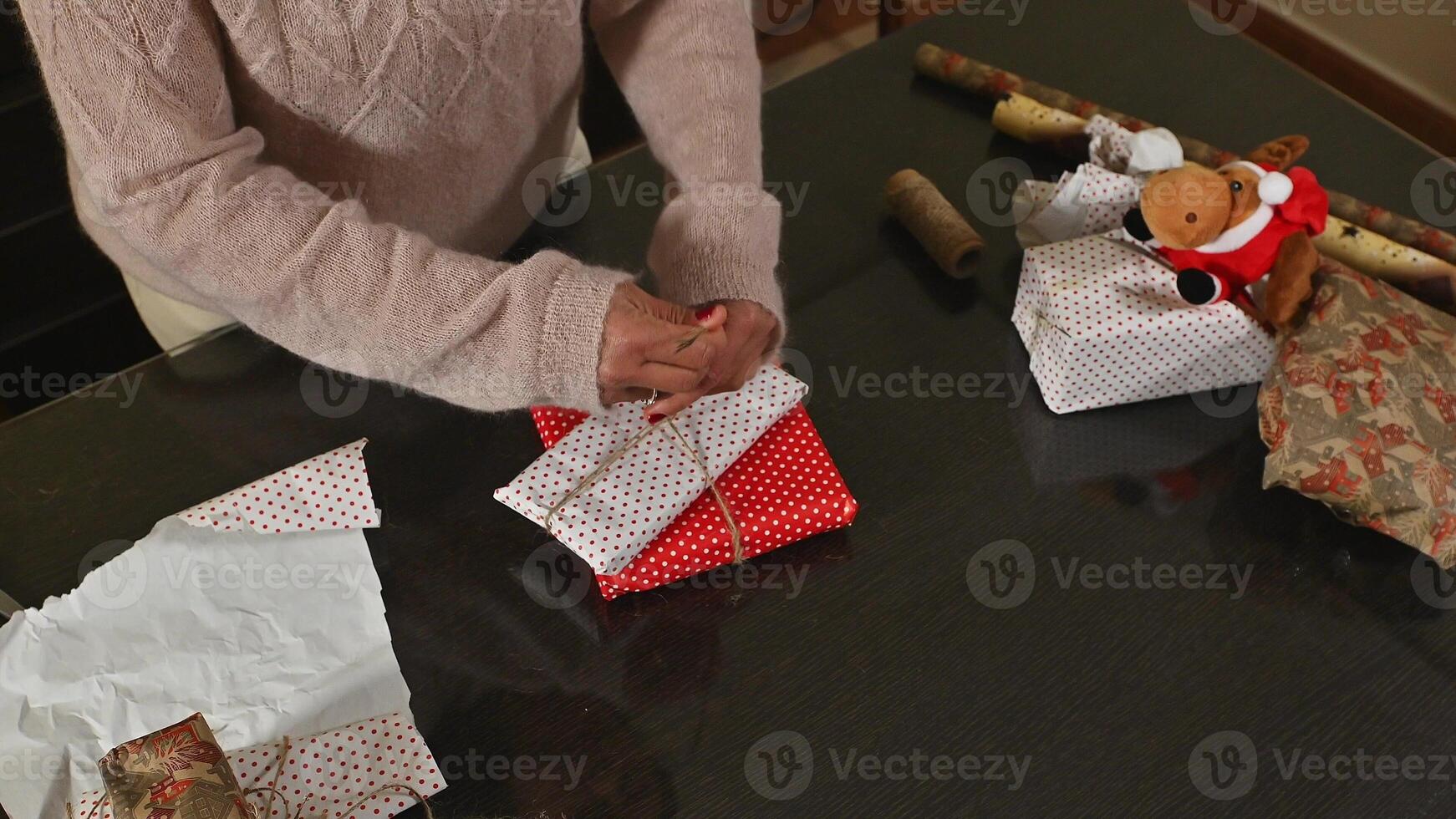 Woman Wrapping Christmas Gifts with Festive Wrapping Paper photo
