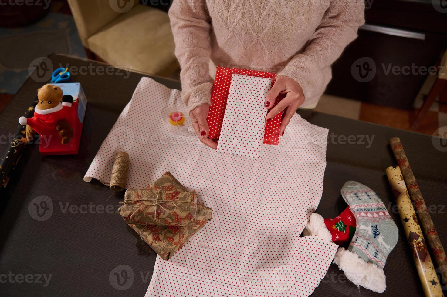 Person Wrapping a Gift with Red Polka Dot Wrapping Paper at Home photo