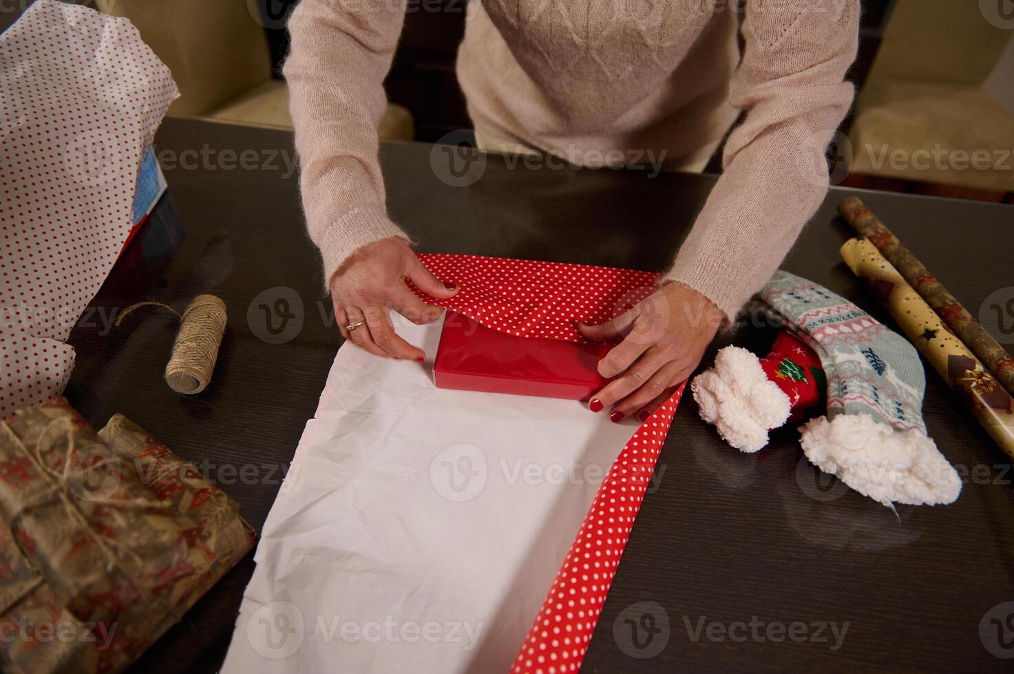Person wrapping a festive gift with red and white wrapping paper photo
