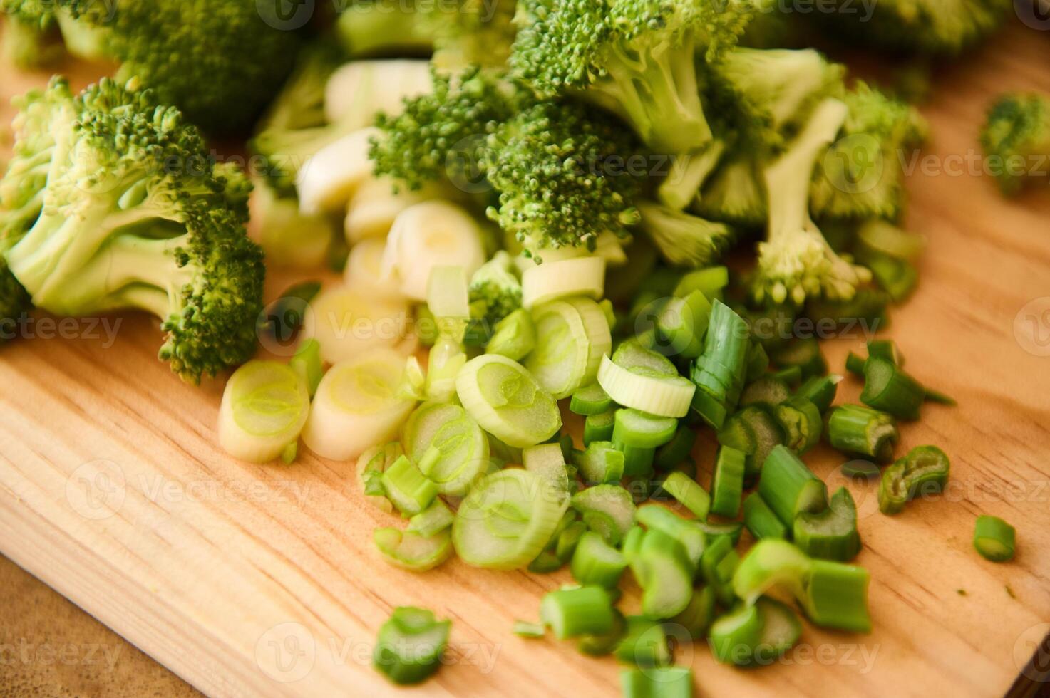 Freshly chopped broccoli and green onions on a wooden cutting board photo