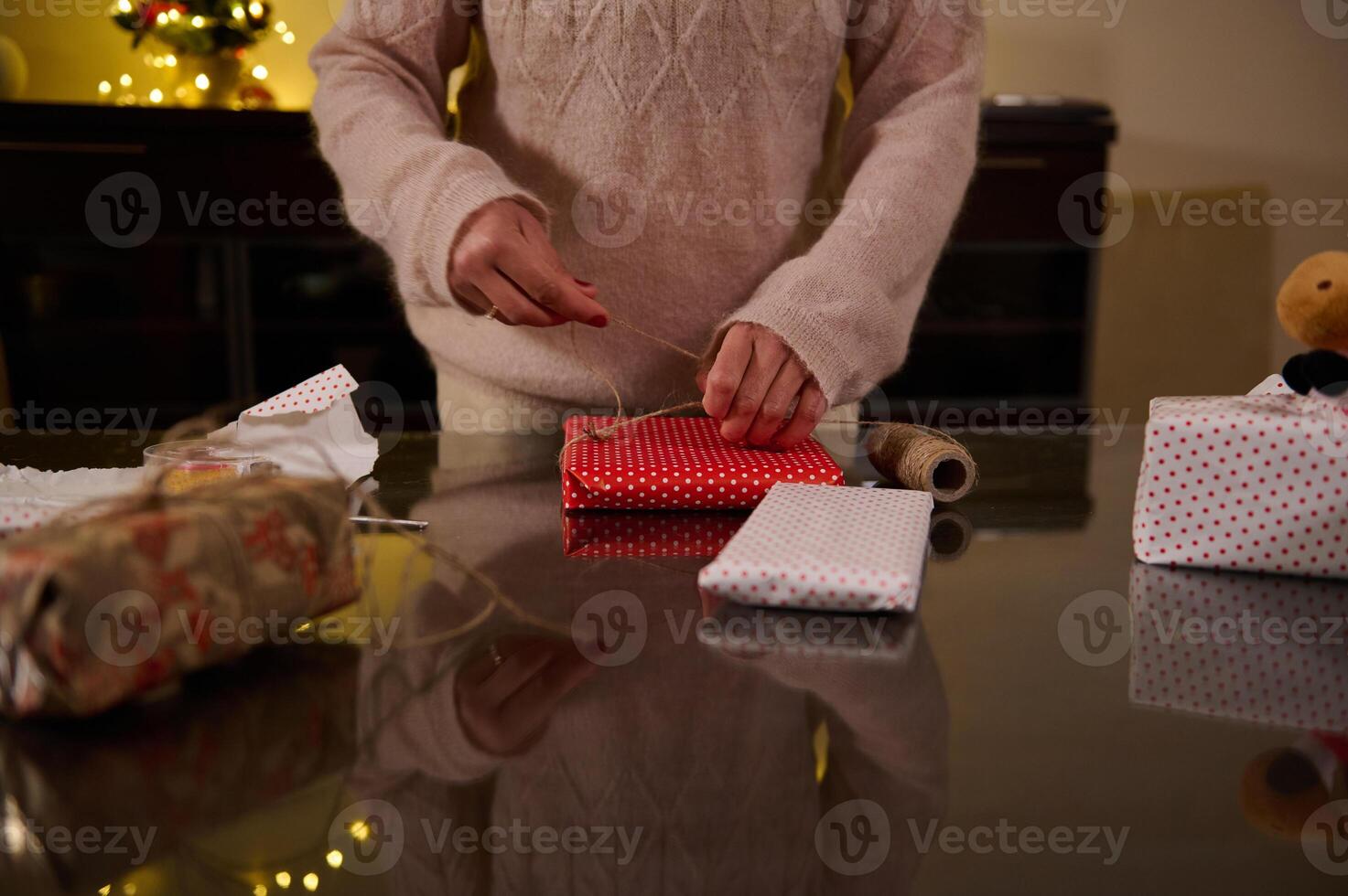 Person wrapping Christmas presents with festive paper and cozy indoor lighting photo