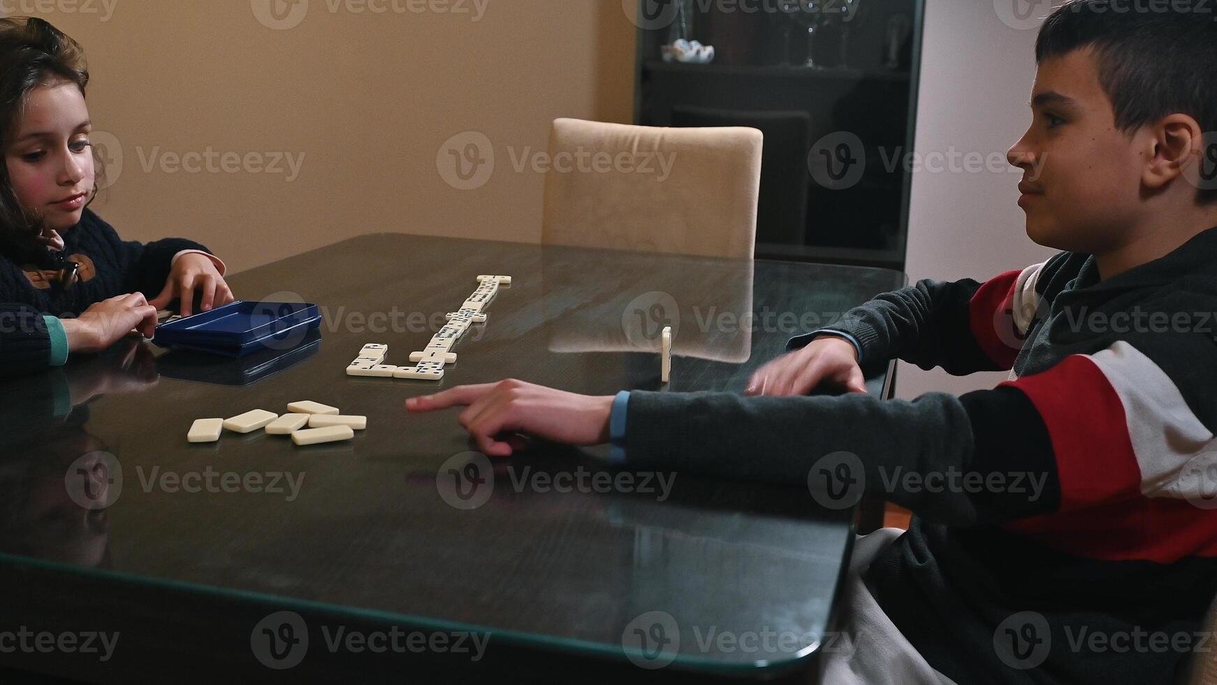 Children engaging in a game of dominoes at a modern dining table photo