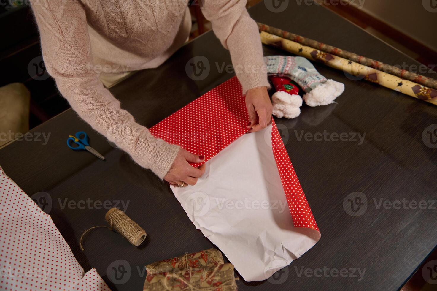 Wrapping holiday gifts with red polka dot paper on a dark table photo