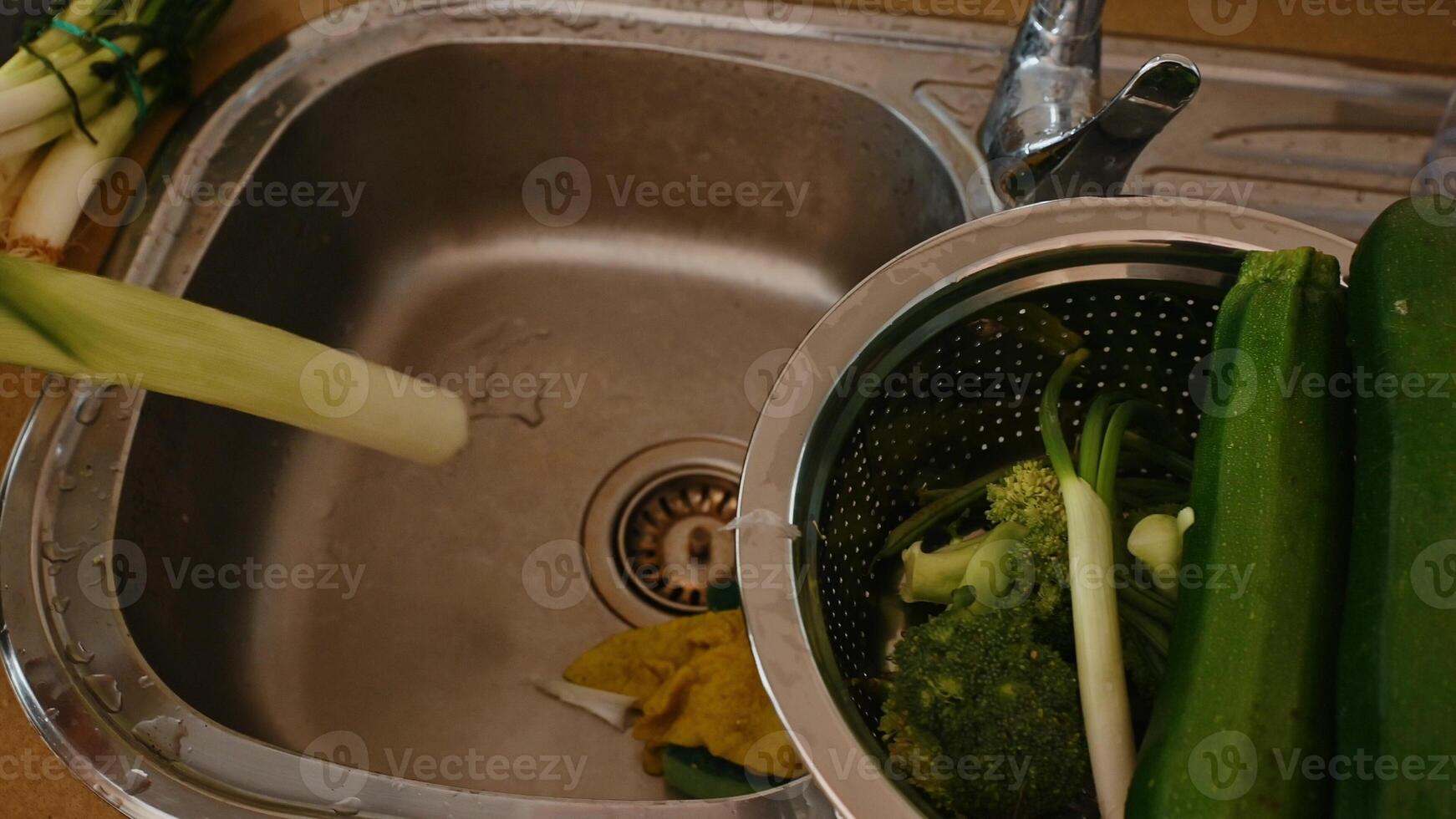 Washing fresh vegetables in a kitchen sink for a healthy meal preparation photo