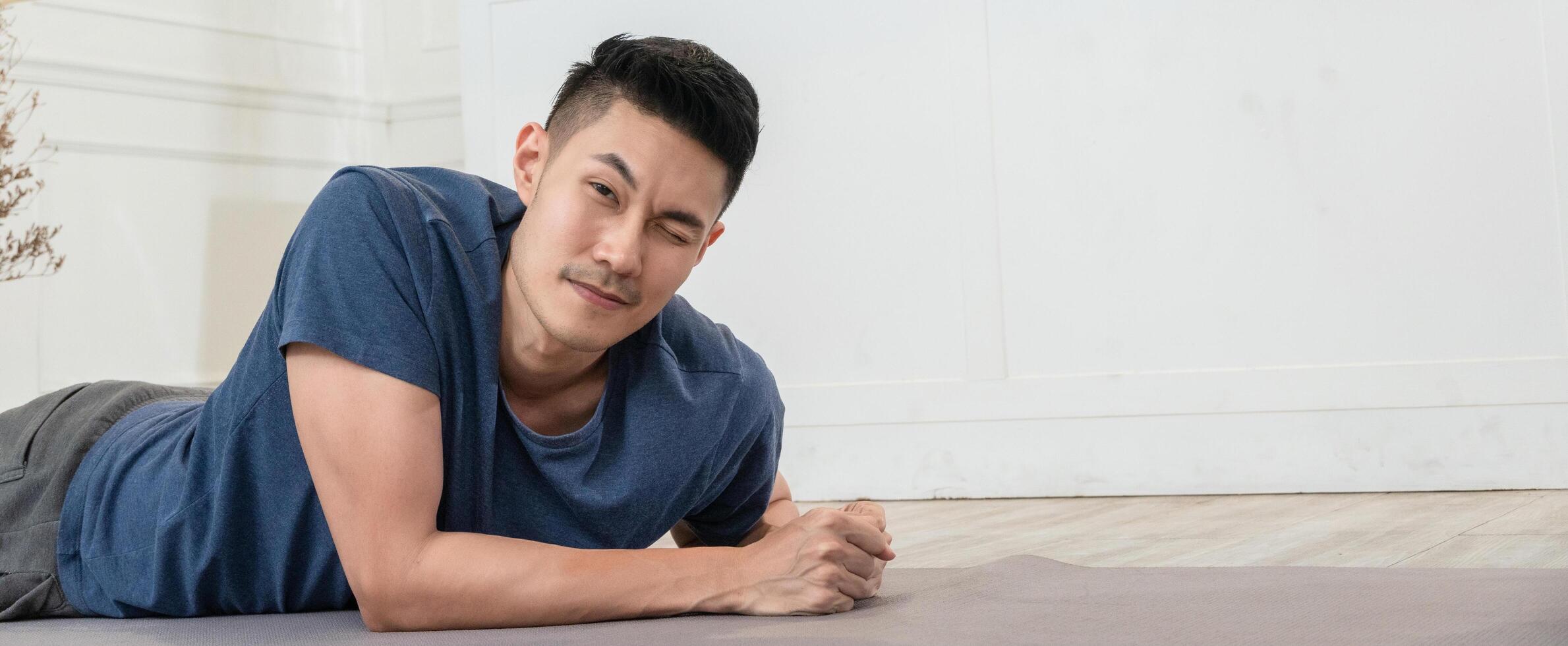 Asian man on the floor for plank exercises winking eye to camera photo