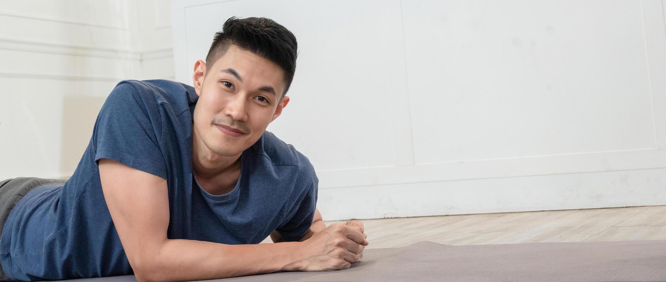 Asian man on the floor for plank exercises looking at camera photo