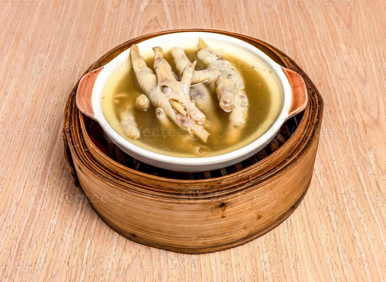 Medicinal Chicken Feet Soup served in bamboo steamer isolated on wooden table side view of hong kong food photo