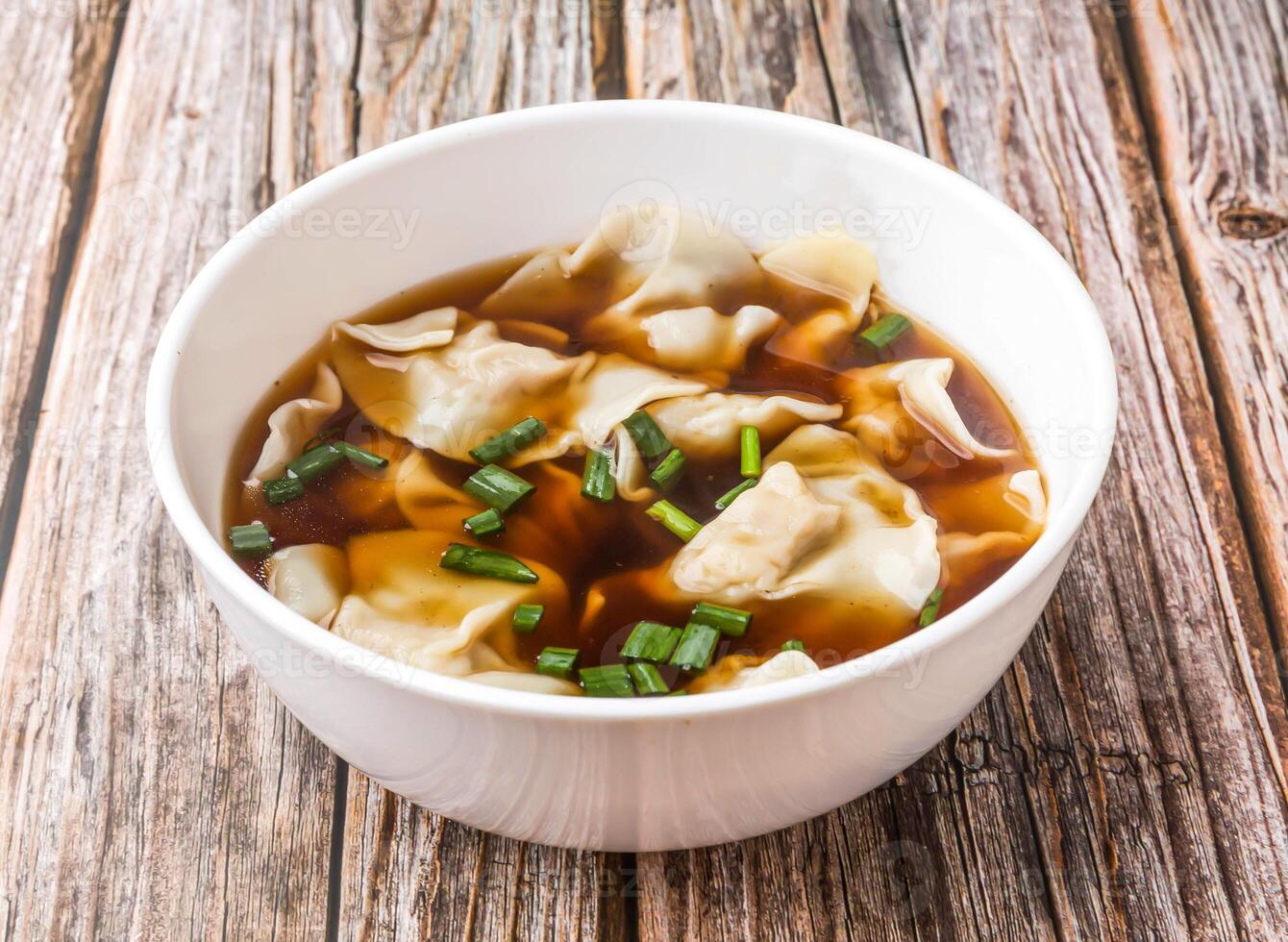 Wonton Soup with Green Onions served in bowl isolated on wooden table side view of hong kong food photo