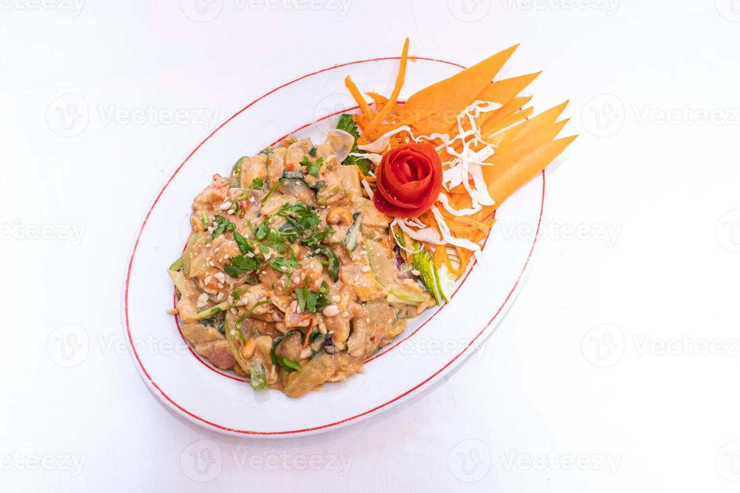 Thai mixed vegetable tossed in a creamy peanut sauce topped with coriander and carrot served on white plate isolated on white background top view of thai and bangladeshi food photo