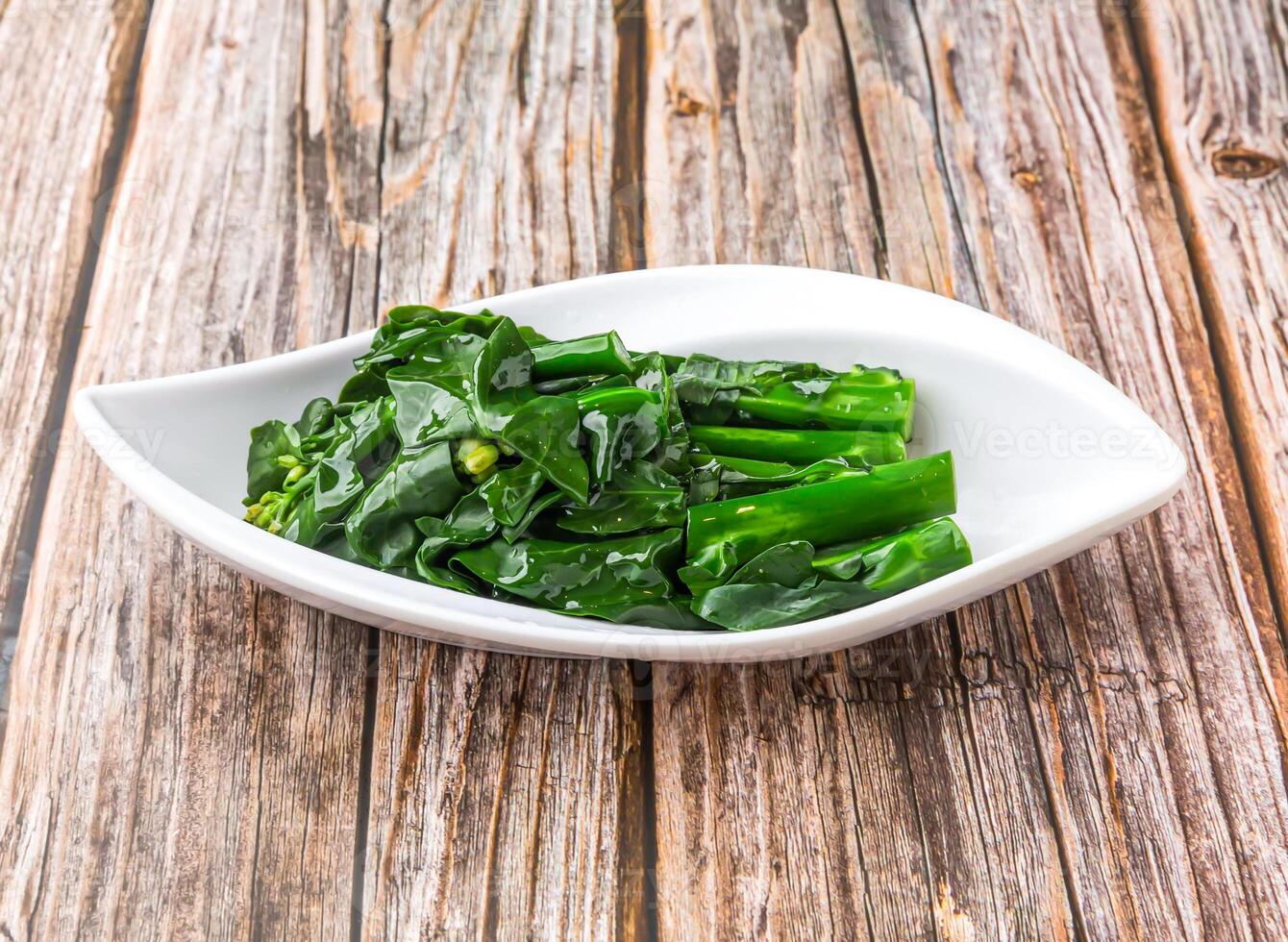 Sauteed Choy Sum or Chinese Broccoli with a touch of garlic and oyster sauce served in dish isolated on wooden table side view of hong kong food photo