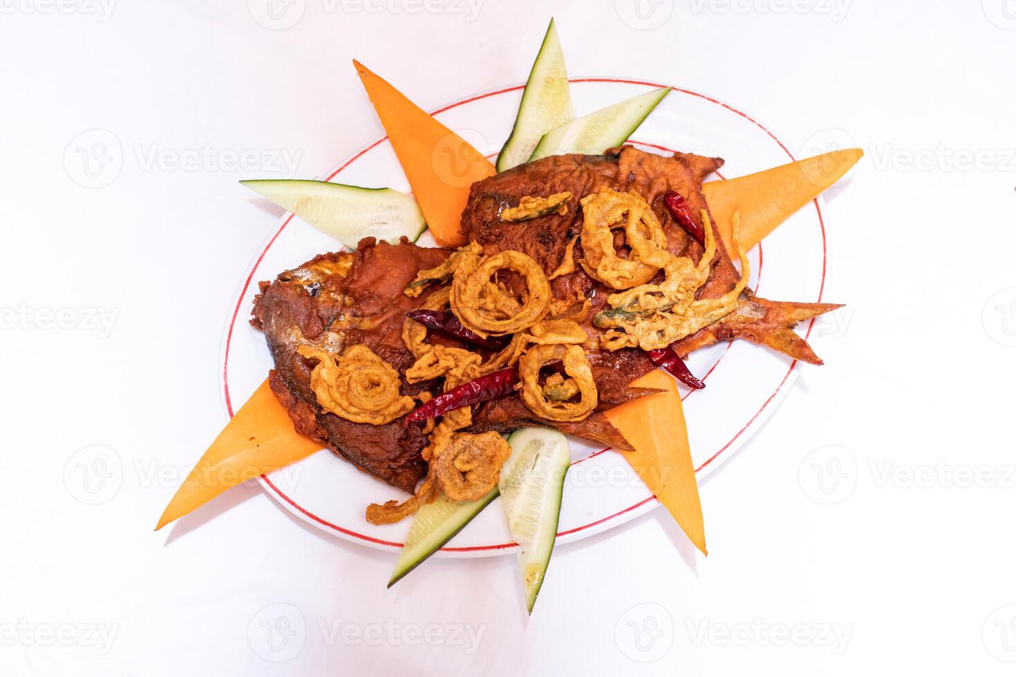 Fried Pomfret Fish garnished with crispy onion rings and red chili peppers served on white plate isolated on white background top view of thai and bangladeshi food photo