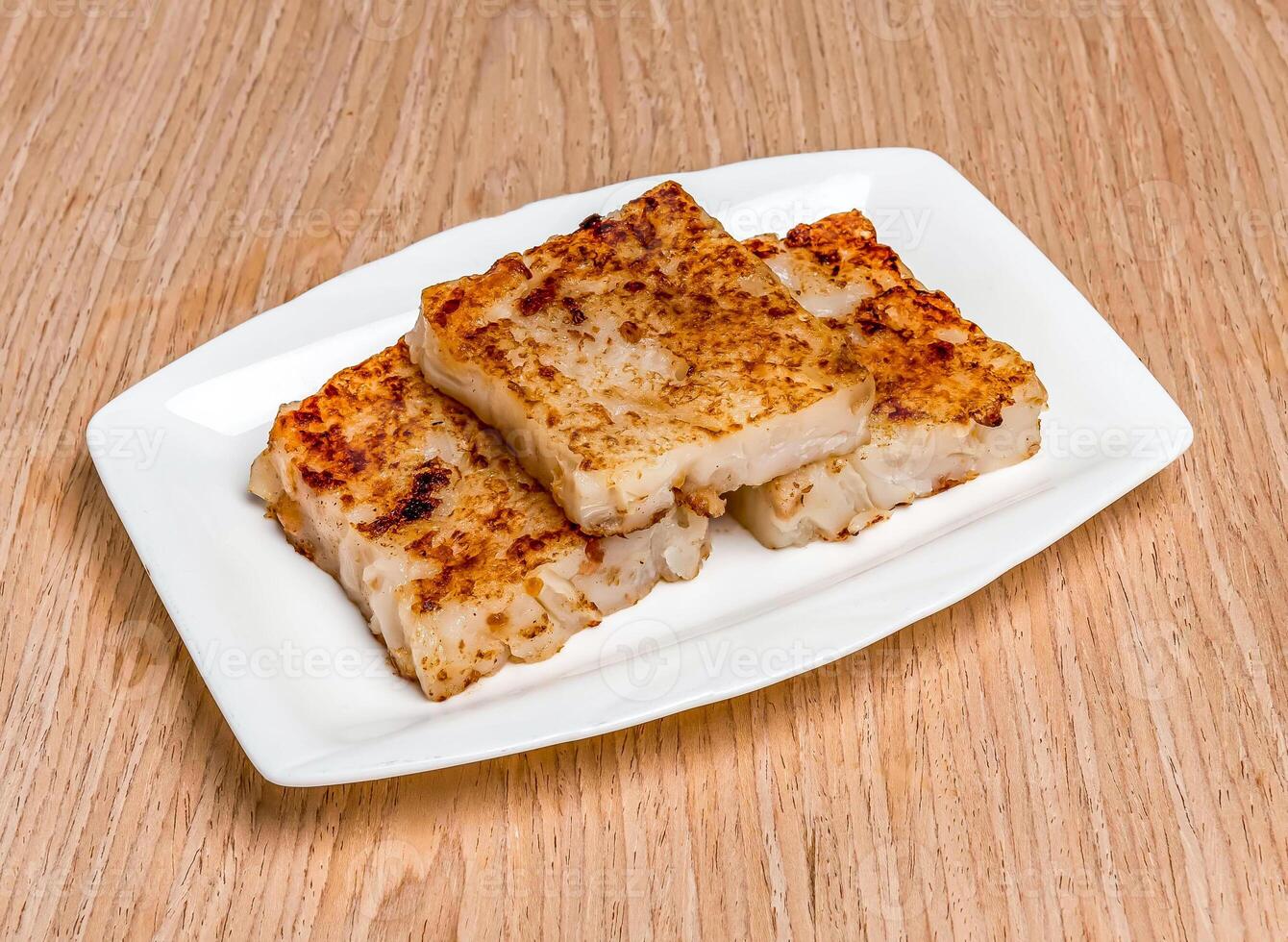 Pan Fried Carrot Cake served in tray isolated on wooden table side view of hong kong food photo