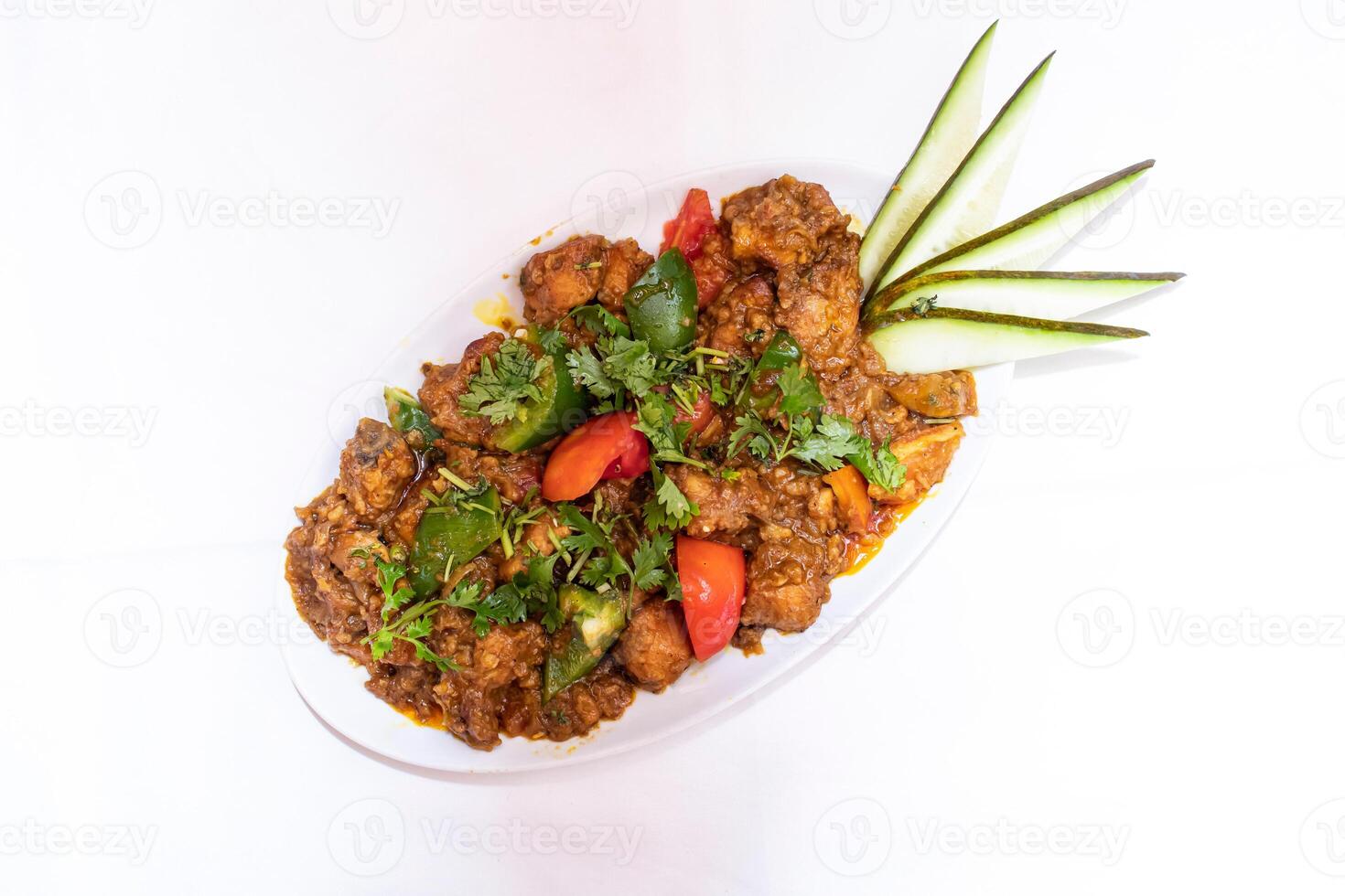 Spicy Chicken Curry topped with tomato, cucumber and coriander served on white plate isolated on white background top view of thai and bangladeshi food photo