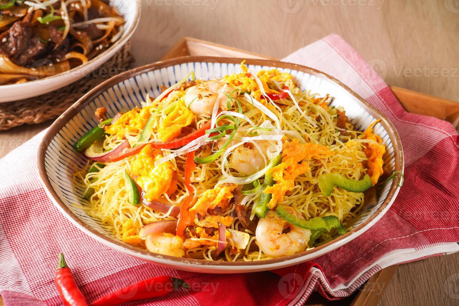 Xing zhou Fried Rice or Singapore Style Fried Rice including shrimp, vegetables, and egg served in pot isolated on napkin side view of hong kong food on wooden background photo