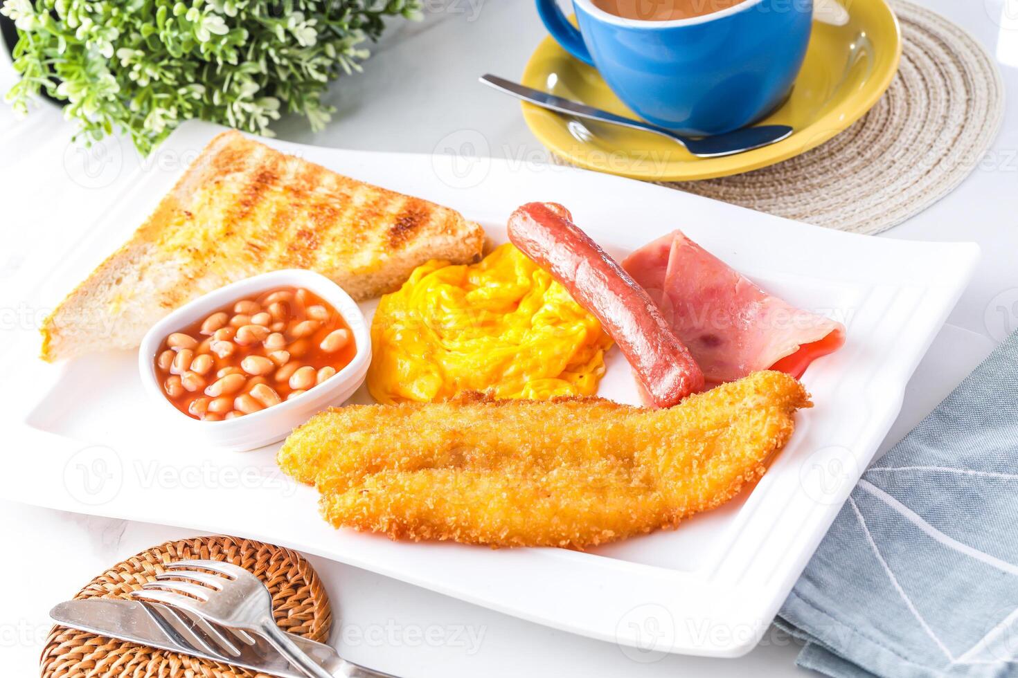 Classic English Breakfast Plate including fried fish, scrambled eggs, sausages, baked beans, toast, and a cup of hot milk tea served in tray isolated on background side view of breakfast meal photo