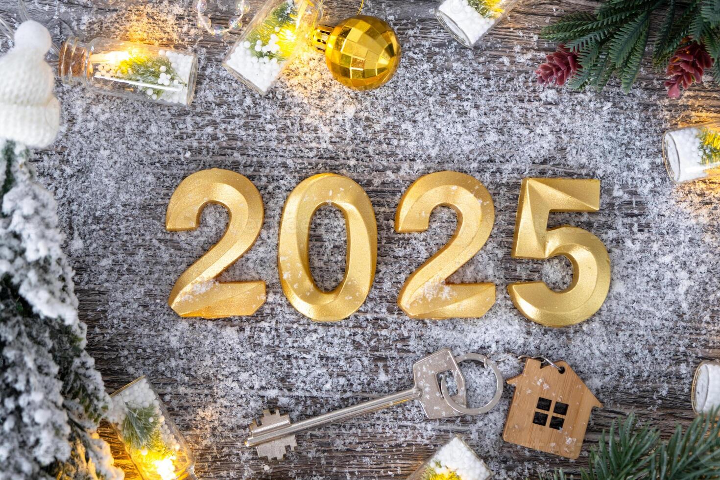New Year 2025 golden numbers and House key with tiny form of home on festive grey wooden background flatlay, lights of garlands, greeting card. Housing, real estate, relocation, mortgage, insurance photo