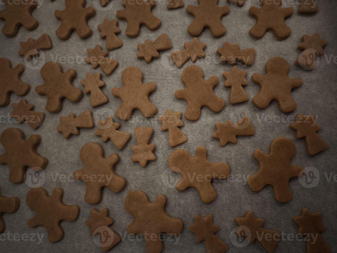 Gingerbread men and comets cookies baking on a tray and paper, ready for the holiday season christmas photo