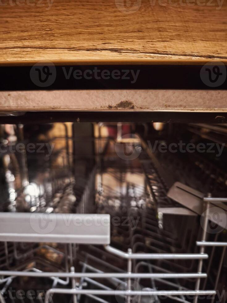 Mold growing underneath kitchen counter on top of dishwasher door photo