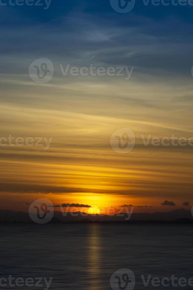 Silhouette mountain with sun and line clouds in sunset sky. photo