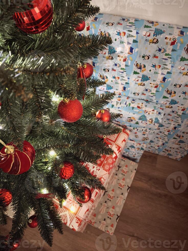 Christmas tree decorated with red baubles and wrapped gifts underneath New Year preparation decor photo