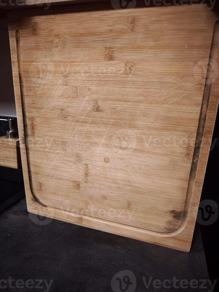 Used bamboo cutting board showing signs of wear and tear in kitchen setting photo