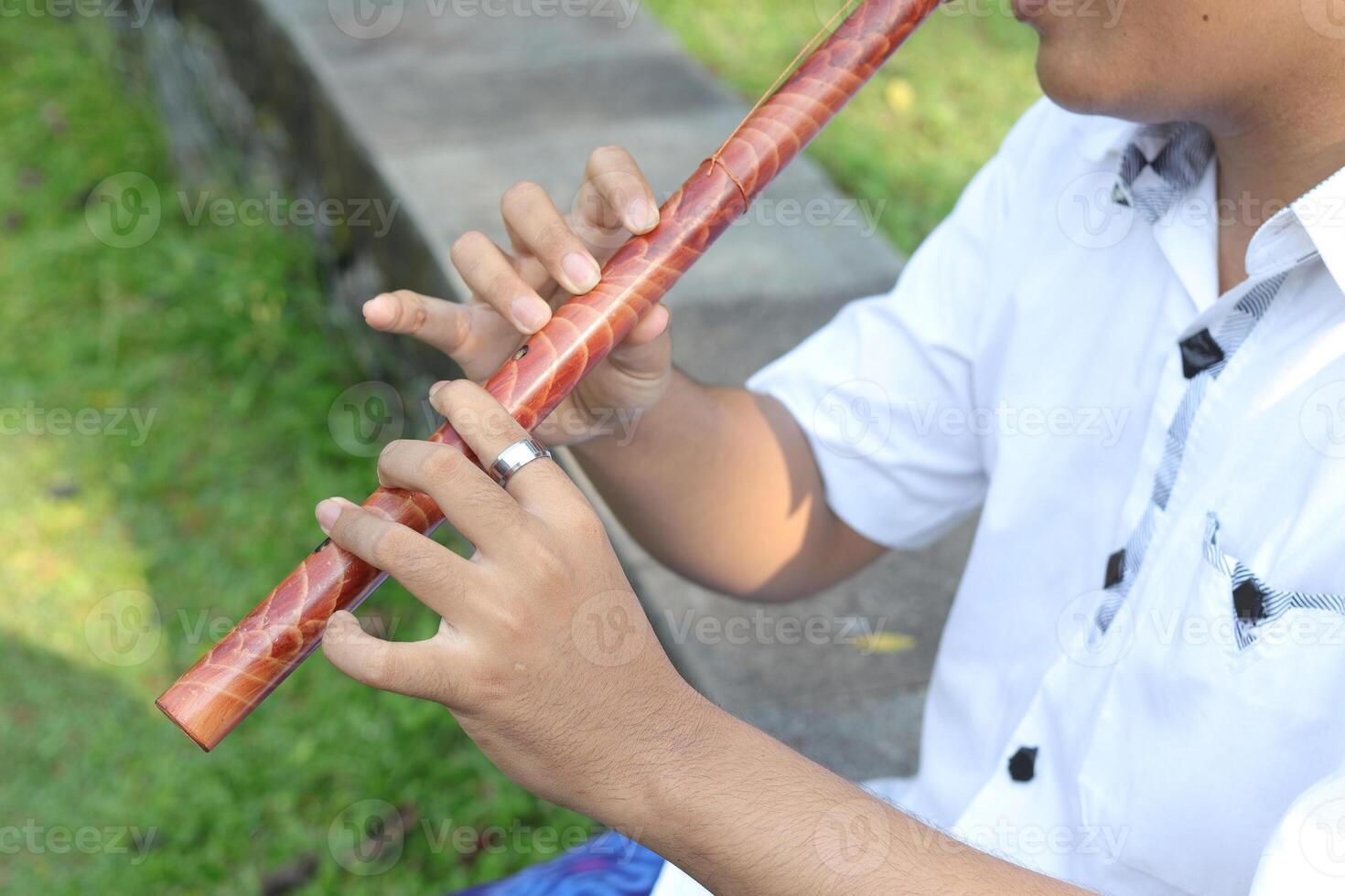 Close up of male hand playing traditional bamboo flute against city park background photo