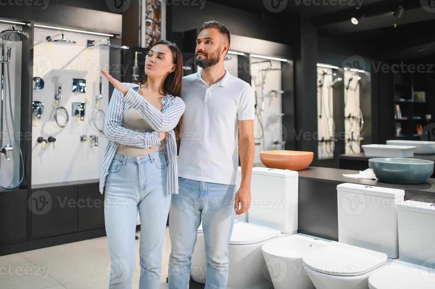 Young couple choosing lavatory pan standing together in the building shop with sanitary ceramics photo