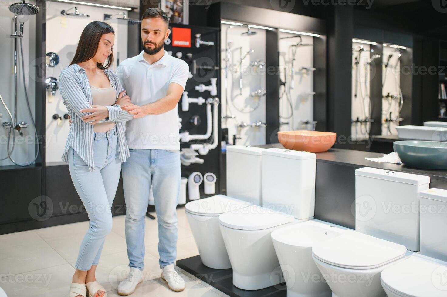 Young couple choosing lavatory pan standing together in the building shop with sanitary ceramics photo