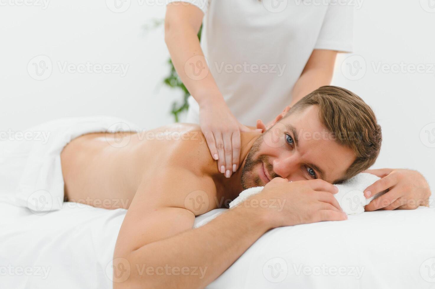 Young man is enjoying massage on spa treatment photo