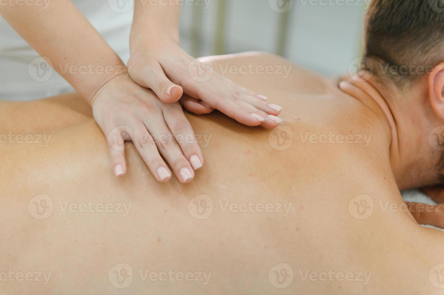 Young man is enjoying massage on spa treatment photo
