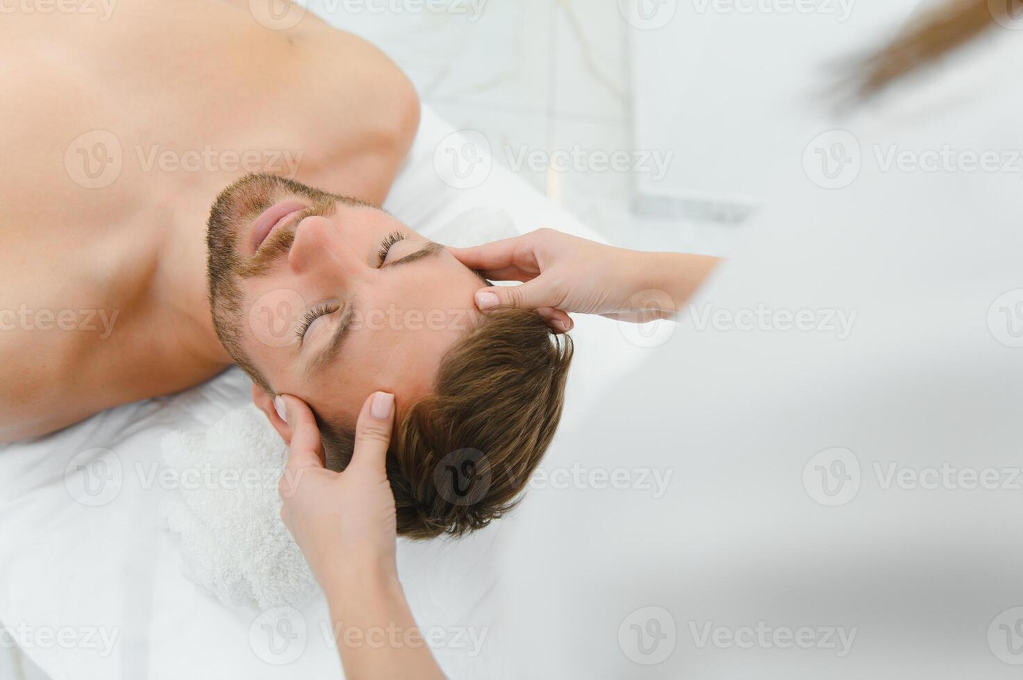 Relaxing anti stress head massage. Handsome man relaxes in a massage parlor during head massage photo