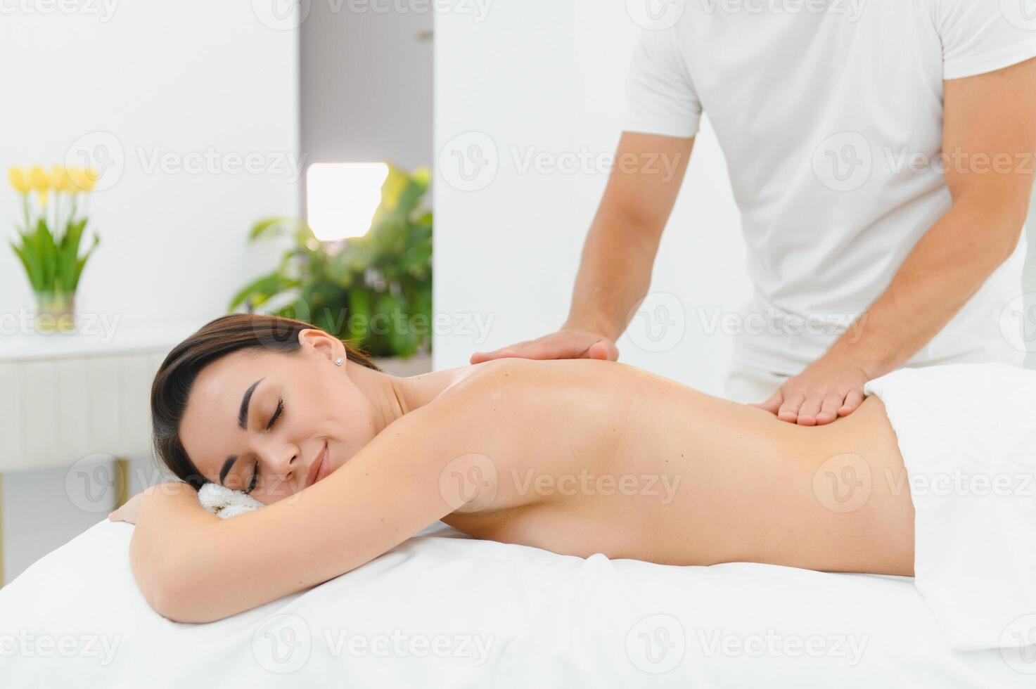 Osteopath massaging back of woman lying on front in health spa photo
