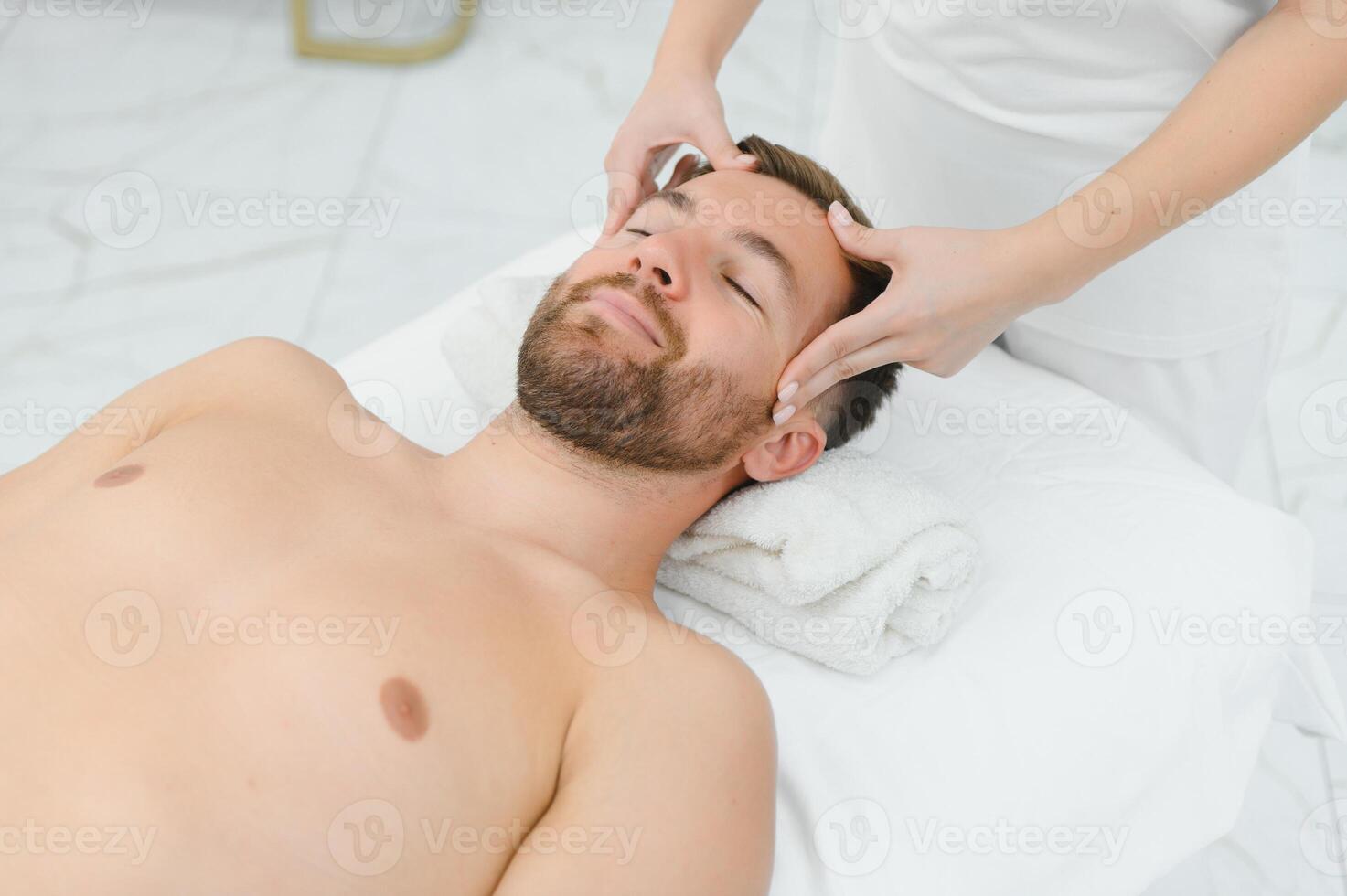 Relaxing anti stress head massage. Handsome man relaxes in a massage parlor during head massage photo