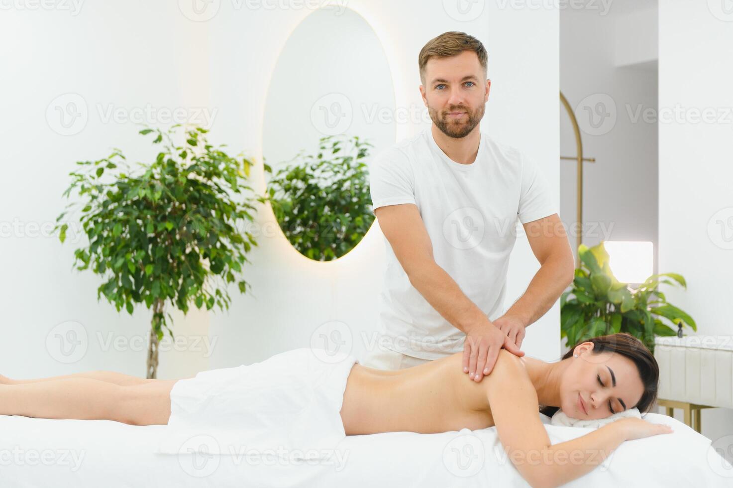 Osteopath massaging back of woman lying on front in health spa photo